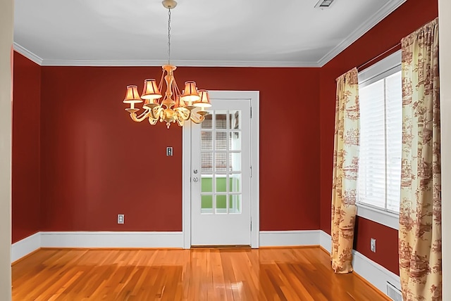 unfurnished dining area with wood-type flooring, ornamental molding, and an inviting chandelier