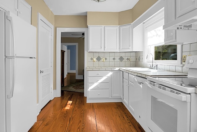 kitchen with white appliances, white cabinets, extractor fan, dark wood-type flooring, and decorative backsplash