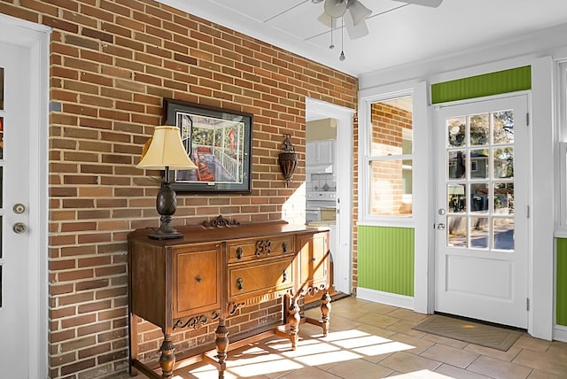 interior space with ceiling fan, brick wall, and light tile patterned flooring