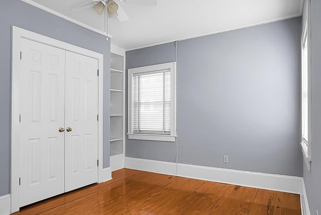 unfurnished bedroom with ceiling fan, wood-type flooring, and a closet