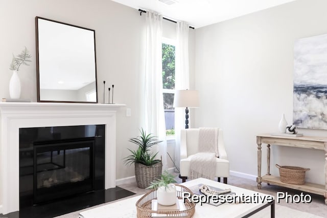 living area with a fireplace with flush hearth, visible vents, and baseboards