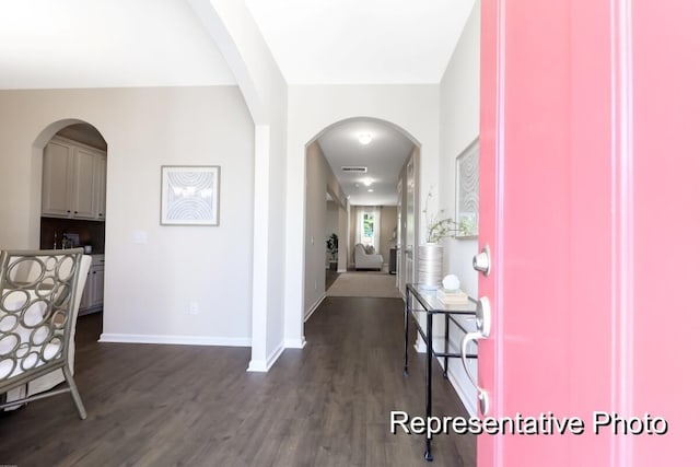 entryway featuring dark wood-style floors, arched walkways, visible vents, and baseboards