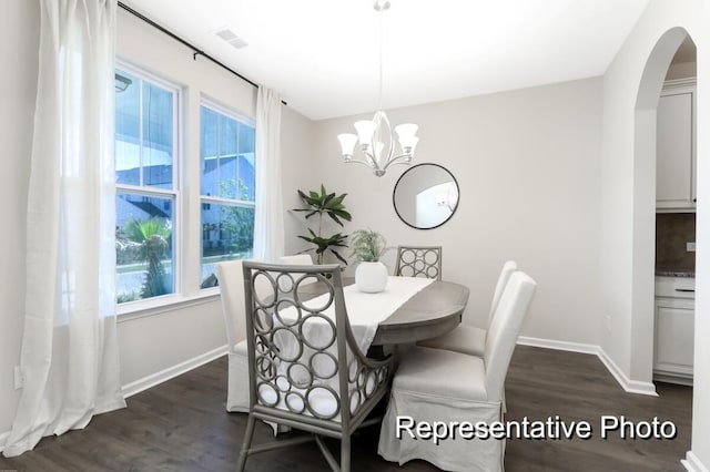 dining area with arched walkways, visible vents, dark wood-type flooring, a chandelier, and baseboards