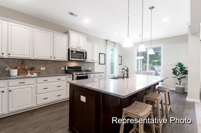 kitchen featuring white cabinets, tasteful backsplash, stainless steel appliances, and a sink