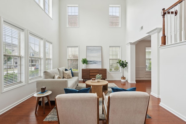 living room featuring plenty of natural light, dark wood finished floors, and a towering ceiling