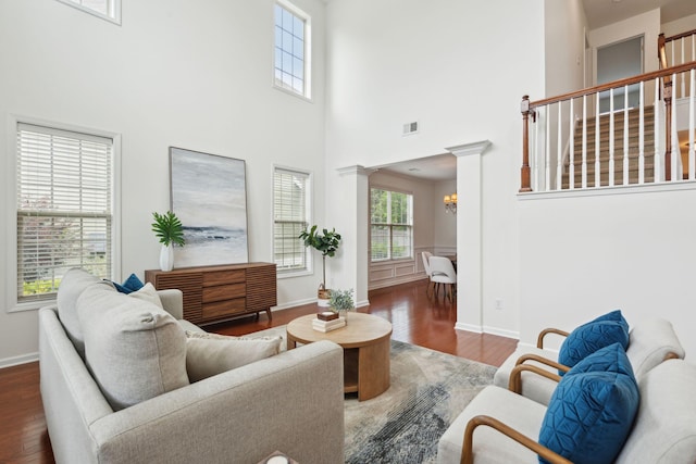 living area featuring wood finished floors, a towering ceiling, baseboards, and a chandelier