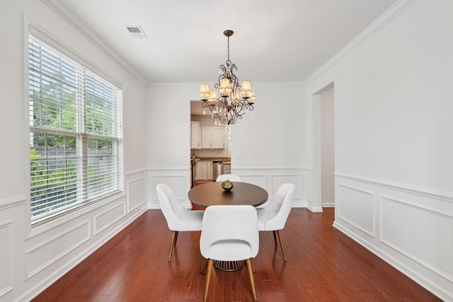 dining room with a chandelier, dark wood-style floors, a decorative wall, a wainscoted wall, and crown molding