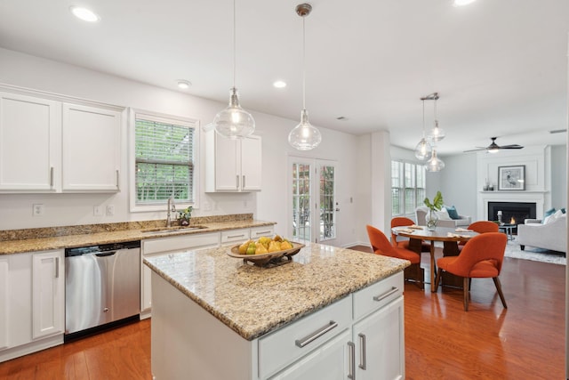 kitchen with dishwasher, a sink, light wood-style flooring, a kitchen island, and white cabinetry