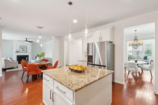 kitchen featuring open floor plan, stainless steel fridge, dark wood finished floors, a lit fireplace, and recessed lighting