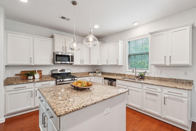 kitchen featuring stainless steel appliances, a sink, recessed lighting, white cabinetry, and a kitchen island