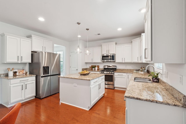 kitchen with appliances with stainless steel finishes, a sink, a center island, white cabinets, and recessed lighting