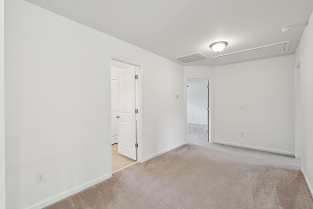 carpeted empty room featuring attic access, baseboards, and a smoke detector