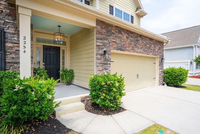 doorway to property with stone siding, an attached garage, and covered porch