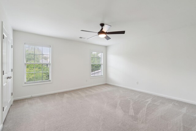 empty room with light colored carpet, baseboards, and ceiling fan