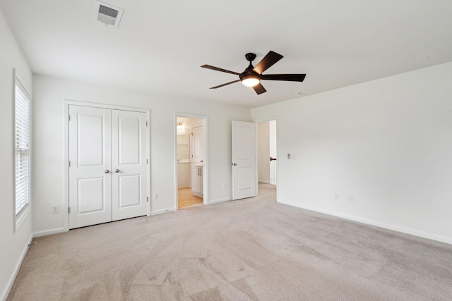 unfurnished bedroom with a closet, light colored carpet, ensuite bath, visible vents, and baseboards