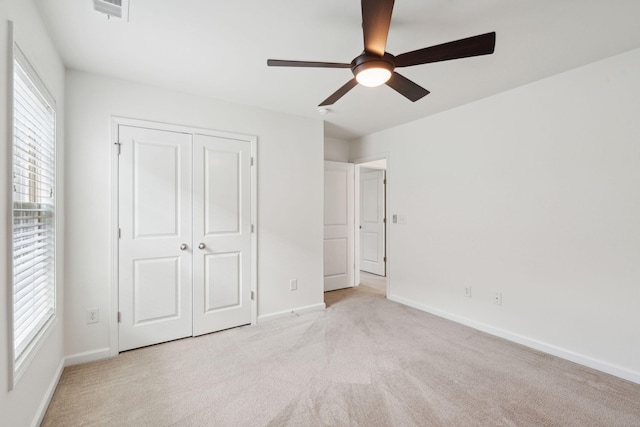 unfurnished bedroom featuring light colored carpet, a closet, baseboards, and visible vents