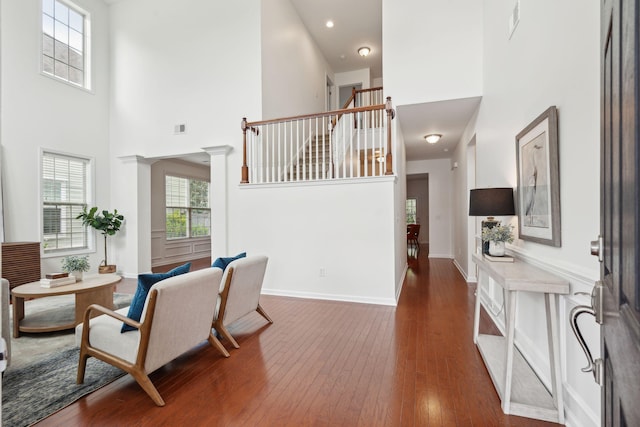 living room featuring a towering ceiling, wood-type flooring, and baseboards