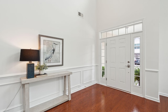 entryway featuring healthy amount of natural light, dark wood finished floors, a decorative wall, and a wainscoted wall