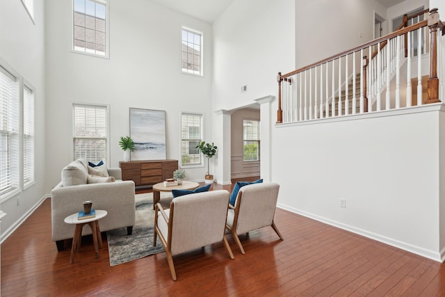 living area featuring wood-type flooring, a high ceiling, baseboards, and plenty of natural light