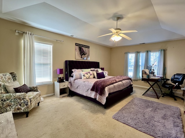 carpeted bedroom featuring a raised ceiling and ceiling fan