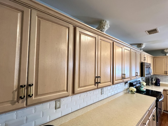 kitchen featuring decorative backsplash, light brown cabinets, and stainless steel electric range