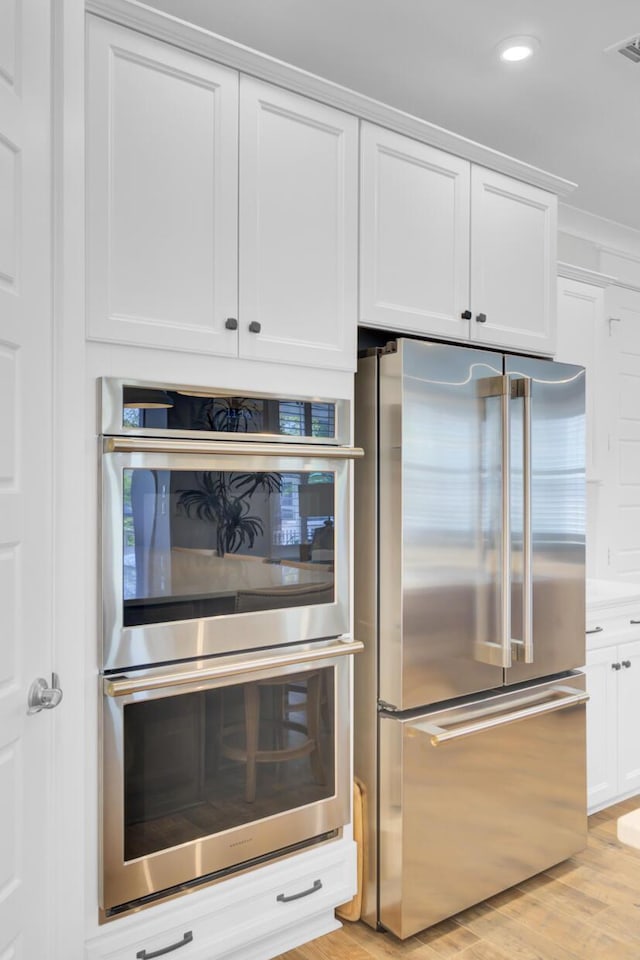 kitchen with white cabinets, appliances with stainless steel finishes, light wood-style flooring, and recessed lighting