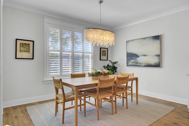 dining area featuring ornamental molding, wood finished floors, a notable chandelier, and baseboards