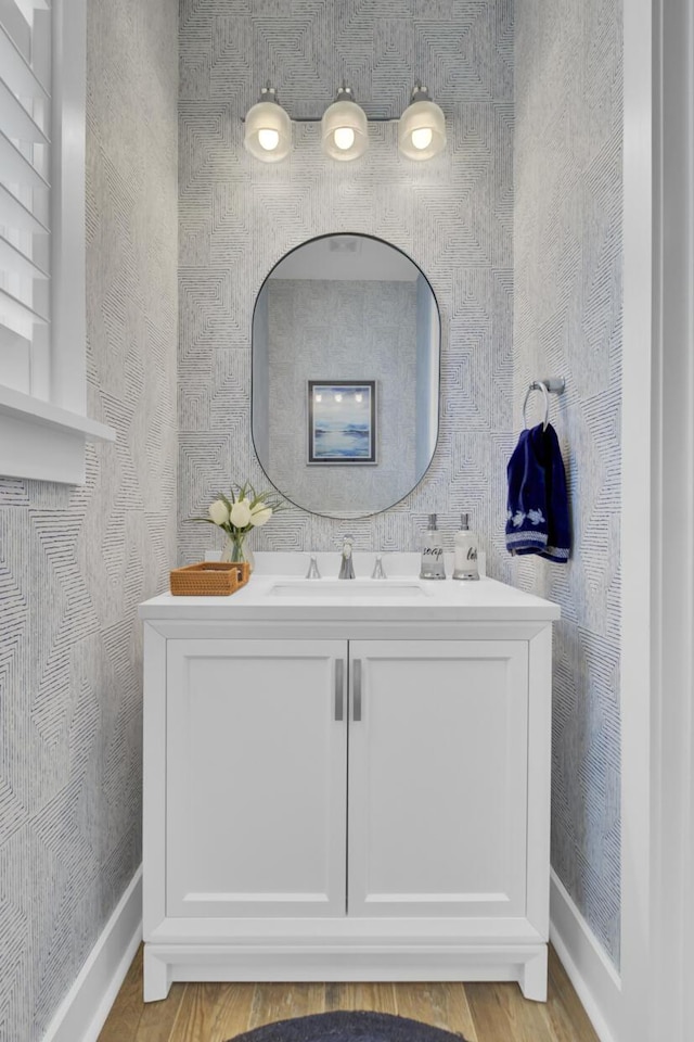bathroom featuring baseboards, wood finished floors, and vanity