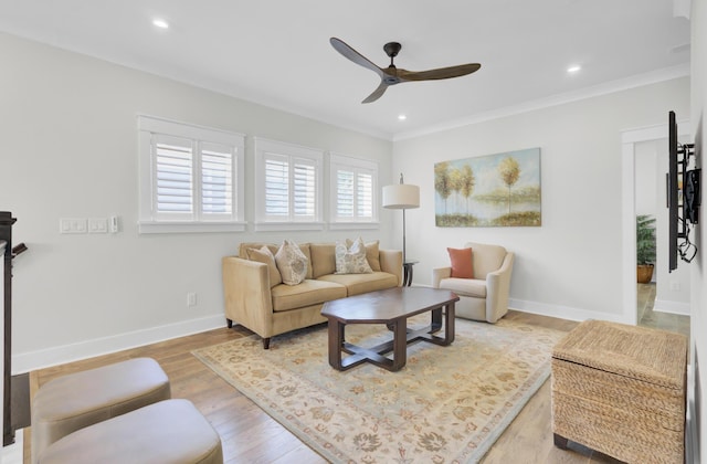 living area with baseboards, light wood-type flooring, recessed lighting, ornamental molding, and a ceiling fan
