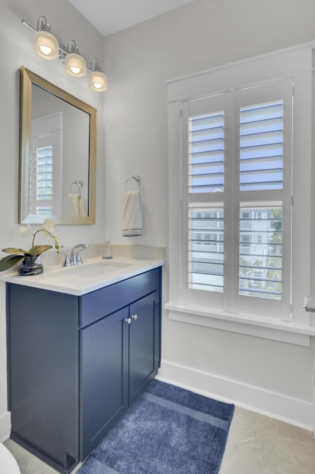 bathroom with baseboards, a healthy amount of sunlight, and vanity