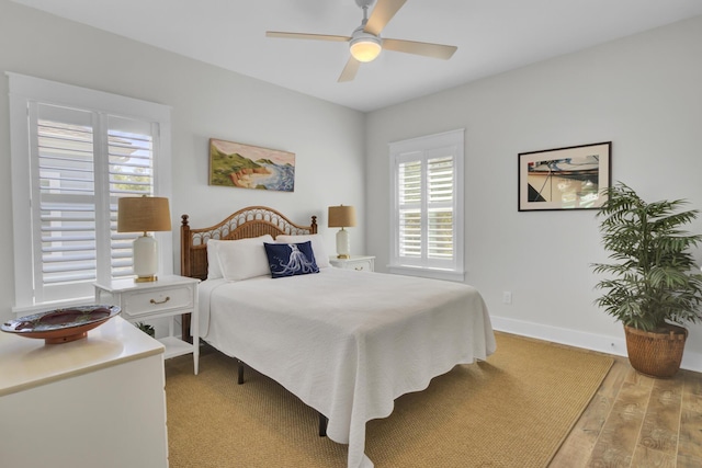 bedroom with ceiling fan, baseboards, light wood finished floors, and multiple windows