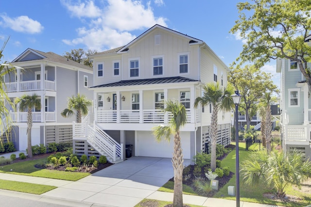 coastal home with a standing seam roof, covered porch, board and batten siding, concrete driveway, and an attached garage