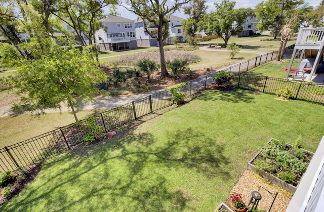 view of yard with a vegetable garden, a residential view, and a fenced backyard