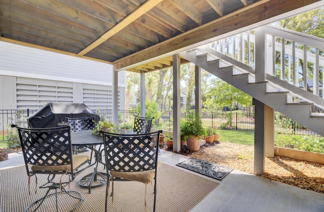 view of patio featuring fence, outdoor dining area, and stairs
