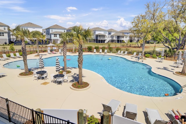 community pool featuring a patio, fence, and a residential view