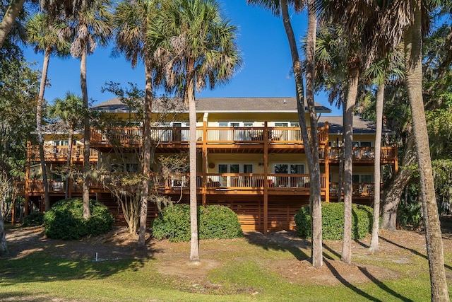 back of property with a wooden deck and a lawn