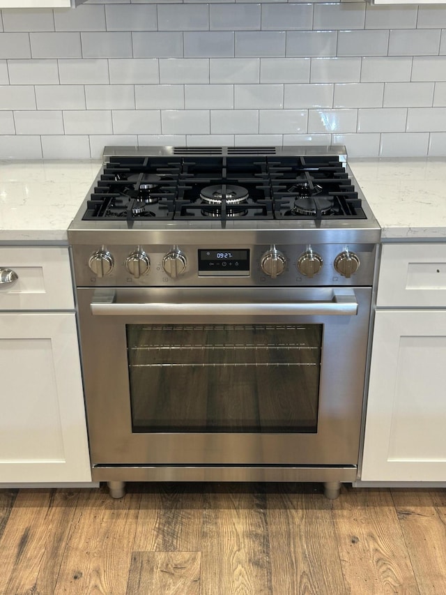 641 Magnolia Rd, Charleston, SC 29407 - kitchen view of stainless steel range with gas stovetop, white cabinetry, tasteful backsplash, and light stone countertops