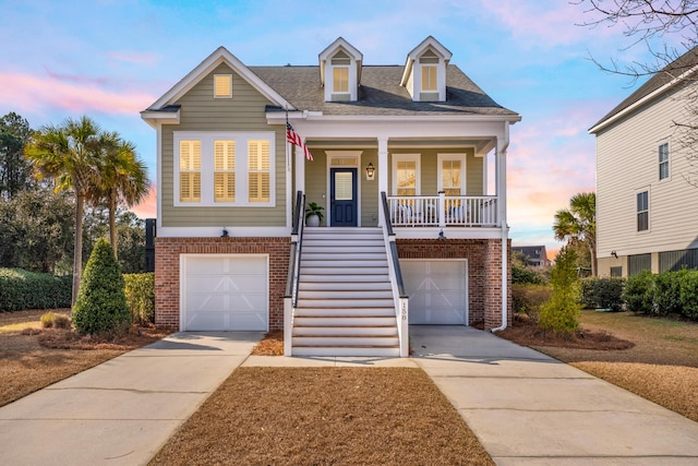 raised beach house with brick siding, an attached garage, stairway, covered porch, and driveway