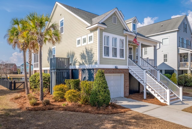 view of front of house featuring stairway, covered porch, concrete driveway, a garage, and brick siding