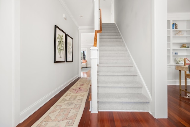 stairs with baseboards, built in shelves, wood finished floors, and crown molding