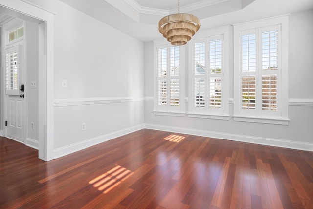 unfurnished dining area featuring a notable chandelier, baseboards, a tray ceiling, and wood finished floors