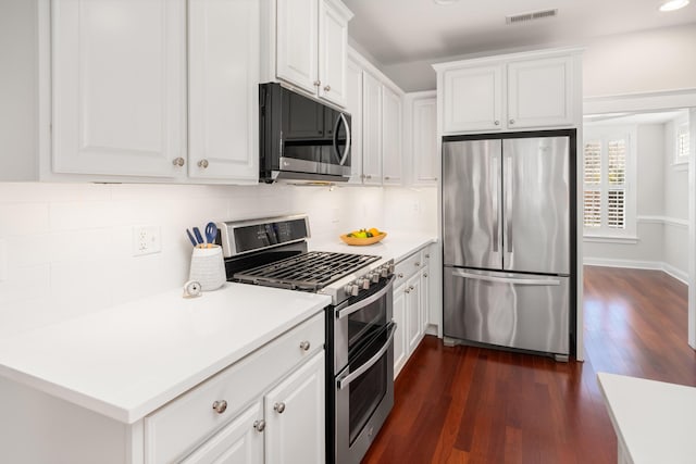 kitchen featuring visible vents, decorative backsplash, appliances with stainless steel finishes, white cabinets, and dark wood-style flooring