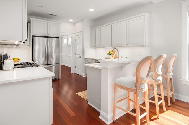 kitchen featuring visible vents, dark wood finished floors, freestanding refrigerator, a peninsula, and light countertops