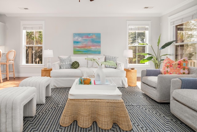 living area with crown molding, wood finished floors, baseboards, and visible vents