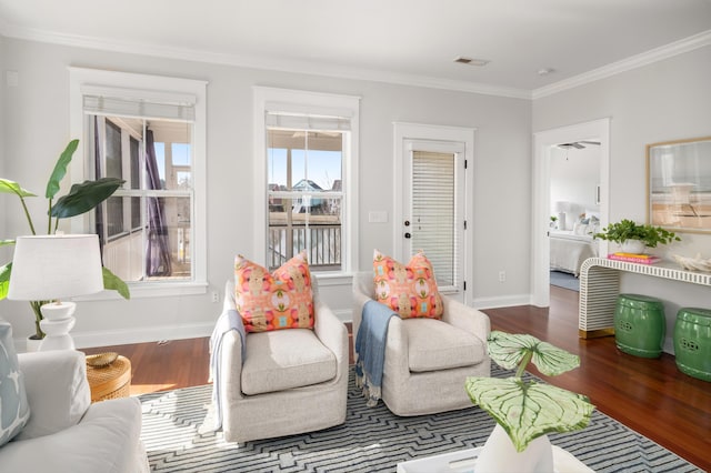 living area with visible vents, ornamental molding, baseboards, and wood finished floors