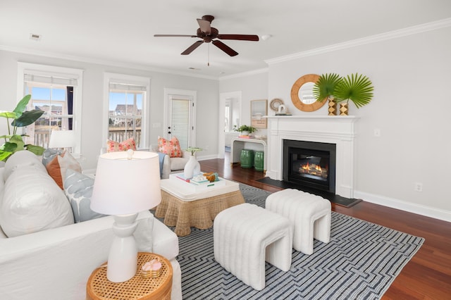 living room featuring baseboards, crown molding, ceiling fan, and wood finished floors