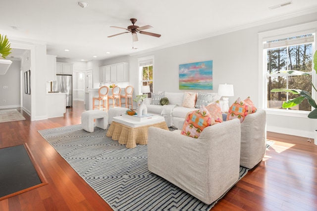 living area with visible vents, ornamental molding, a ceiling fan, wood-type flooring, and baseboards