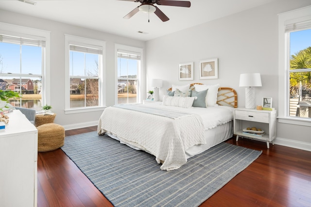 bedroom featuring visible vents, baseboards, dark wood finished floors, and a ceiling fan