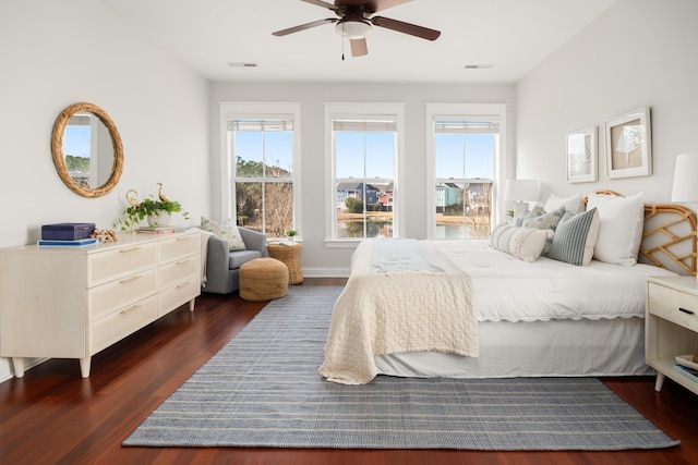 bedroom with dark wood finished floors, visible vents, baseboards, and ceiling fan