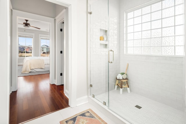 ensuite bathroom featuring baseboards, ceiling fan, a stall shower, ensuite bathroom, and wood finished floors